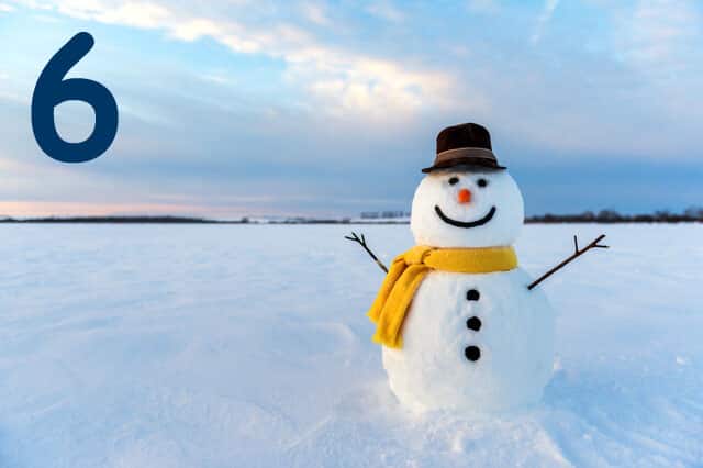 Schneemann auf Schneebedeckem Feld vor Sonnenuntergang