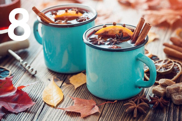 Glühwein in hellblauen Tassen auf Holztisch mit Herbstlaub