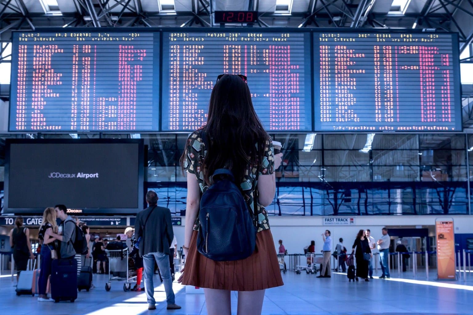 Junge Frau mit Rucksack im Flughafen vor einer Anzeigetafel - Flugreise