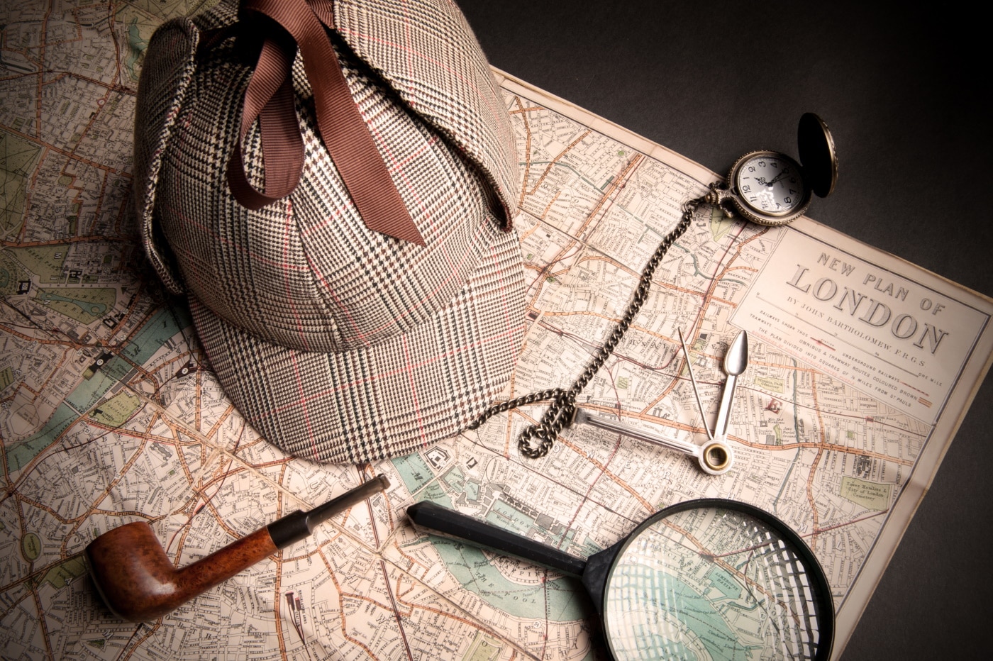 Sherlock Homes Mütze, Lupe, Uhr und weitere Utensilien auf einer Karte von London