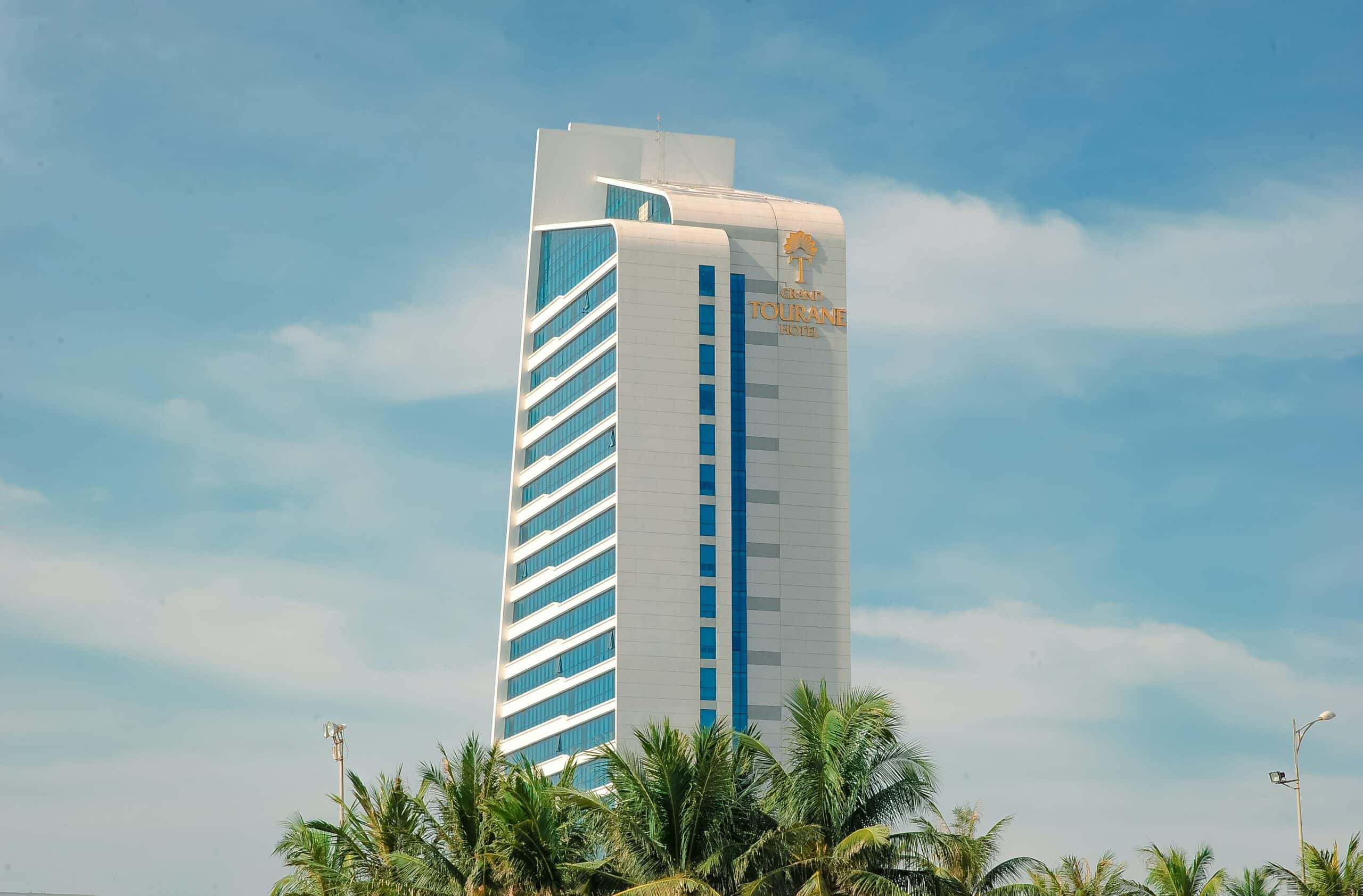 weißer Hotelturm hinter Palmen