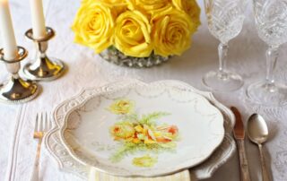 nostalgisches Tischgedeck mit gelben Rosen und bemaltem Teller und geschliffenen Gläsern