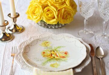 nostalgisches Tischgedeck mit gelben Rosen und bemaltem Teller und geschliffenen Gläsern