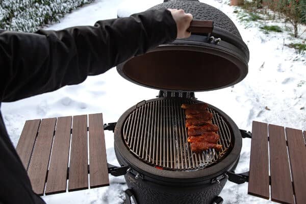 Kugelgrill mit marinierten Hühnerschenkel im Schnee