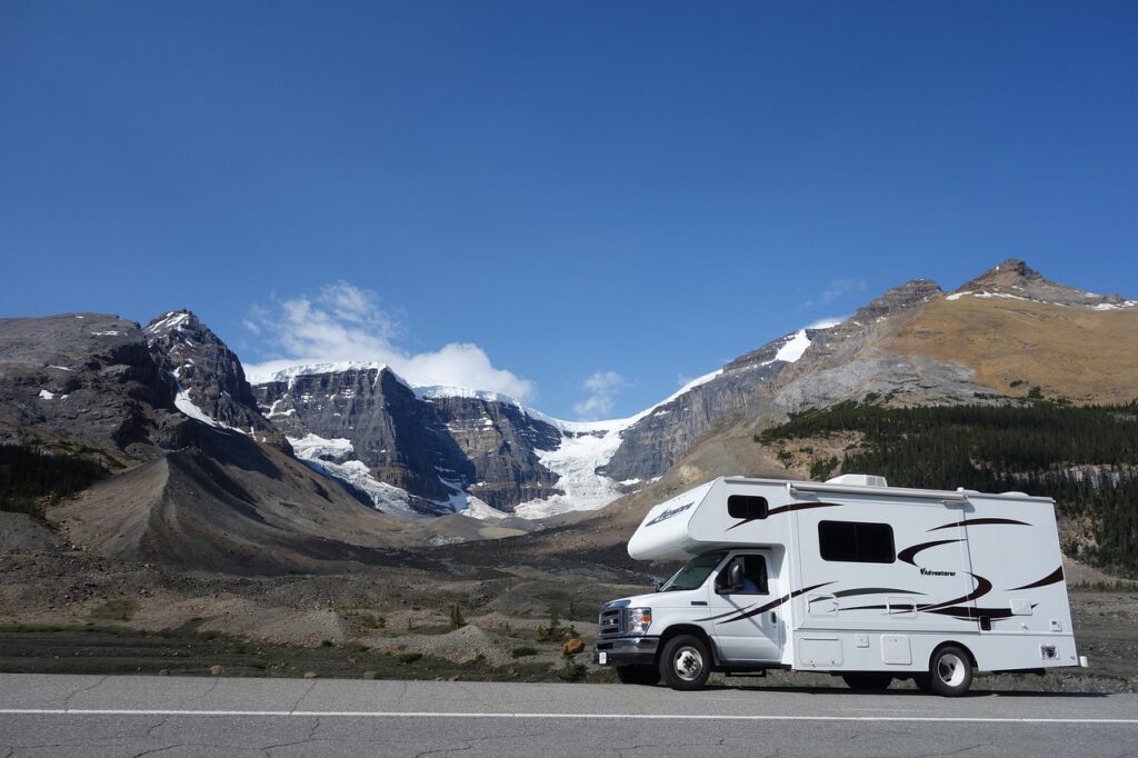 Campermobil auf einer Straße im Hintergrund ein Bergmassiv mit Gletscher. Der Himmel ist blau.