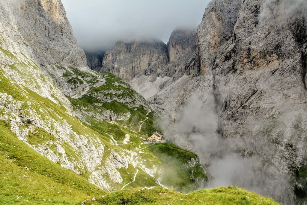 Wanderpfad in den Dolomiten zur Grasleitenhütte oder Refugio Bergamo die markanten Berggipfel liegen im Nebel, am Ende des Pfads liegt eine Steinhütte