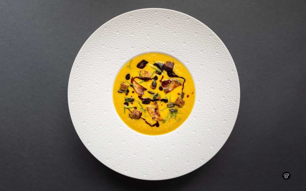 Rezeptbild für traditionelle Kürbissuppe in weißem Suppenteller mit breitem Rand