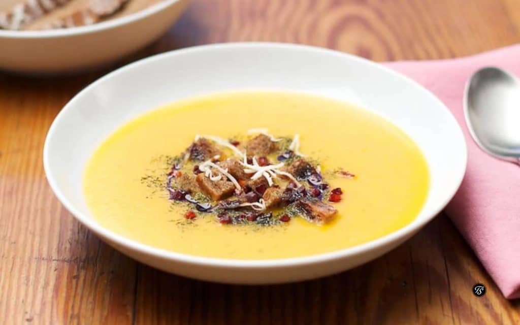 Österreichische Kürbissuppe in weißer Suppenschale auf Holztisch