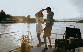 Junges paar tanzt auf einem Hausboot auf einem Fluß im Sommer