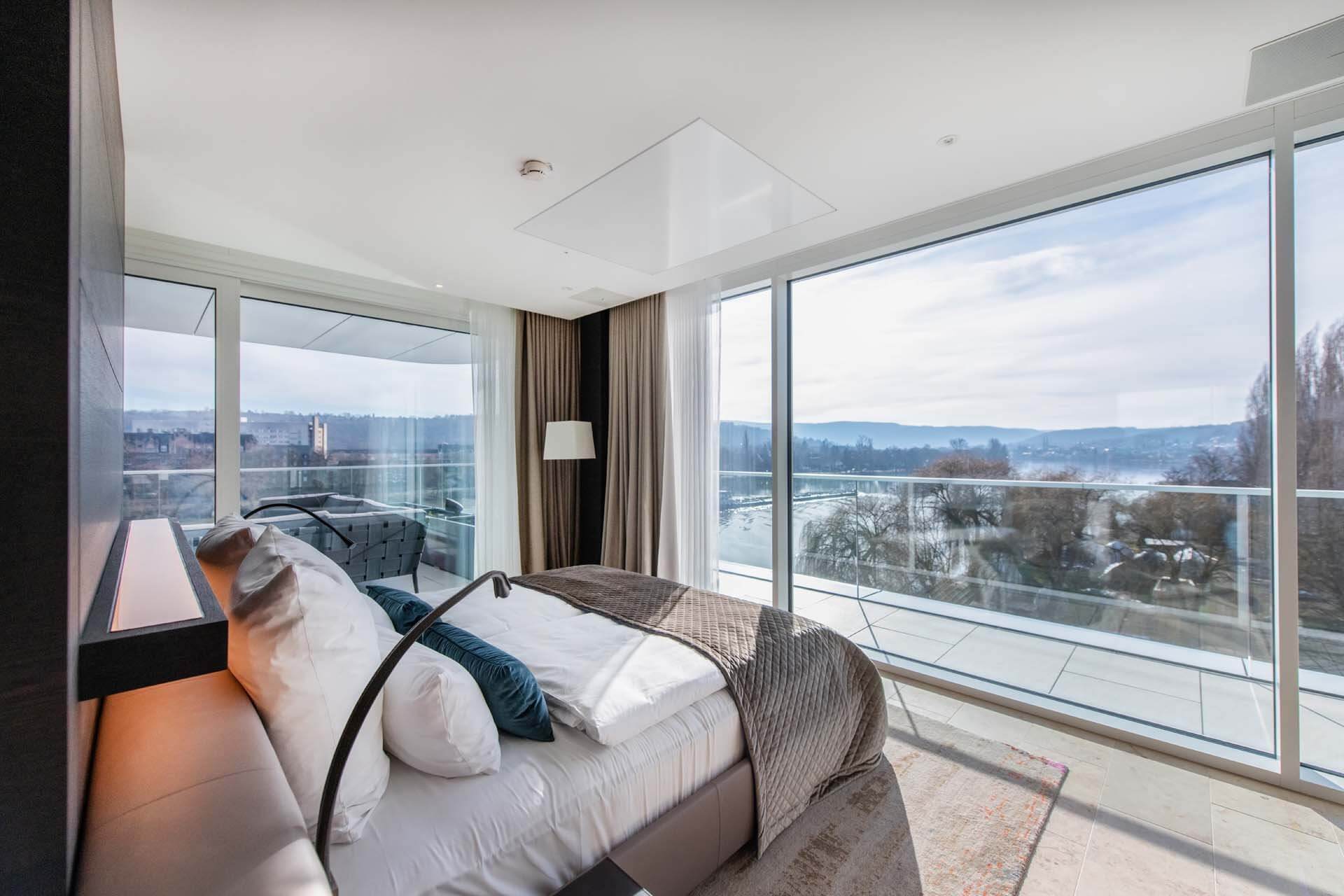 H16246mp_Premium_media_image_4 Modernes Hotelzimmer mit Terrasse und Blick auf einen Fluss.