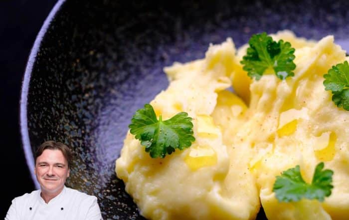 Titelbild Foodblog, Portrait von Thomas Sixt vor dunkler Pfanne mit Kartoffelpüree, der mit Petersilienblättchen dekoriert ist.
