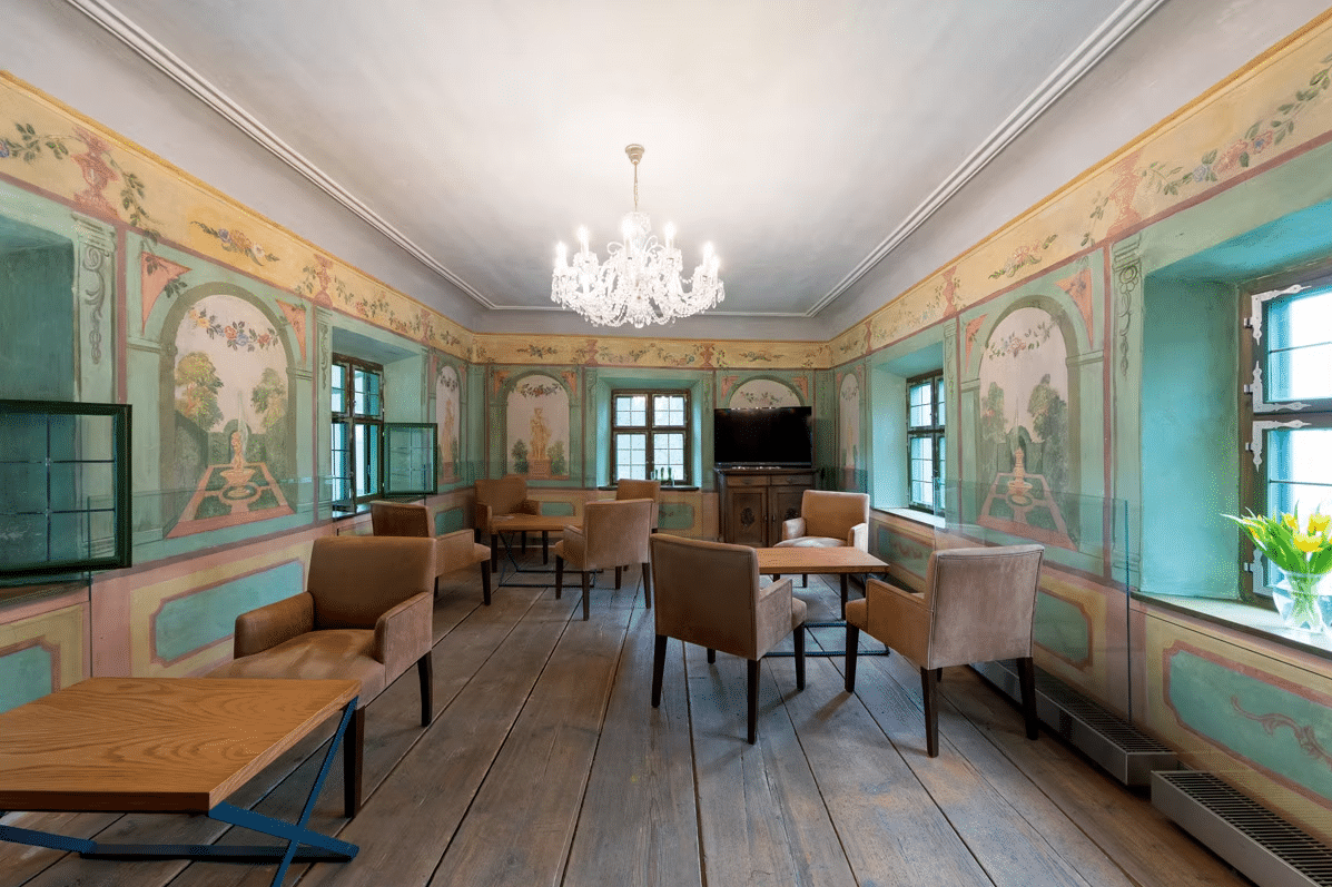 gemütliche Hotellounge mit bequemen Stühlen und Tischen in historschen Zimmer mit Wandbemalung