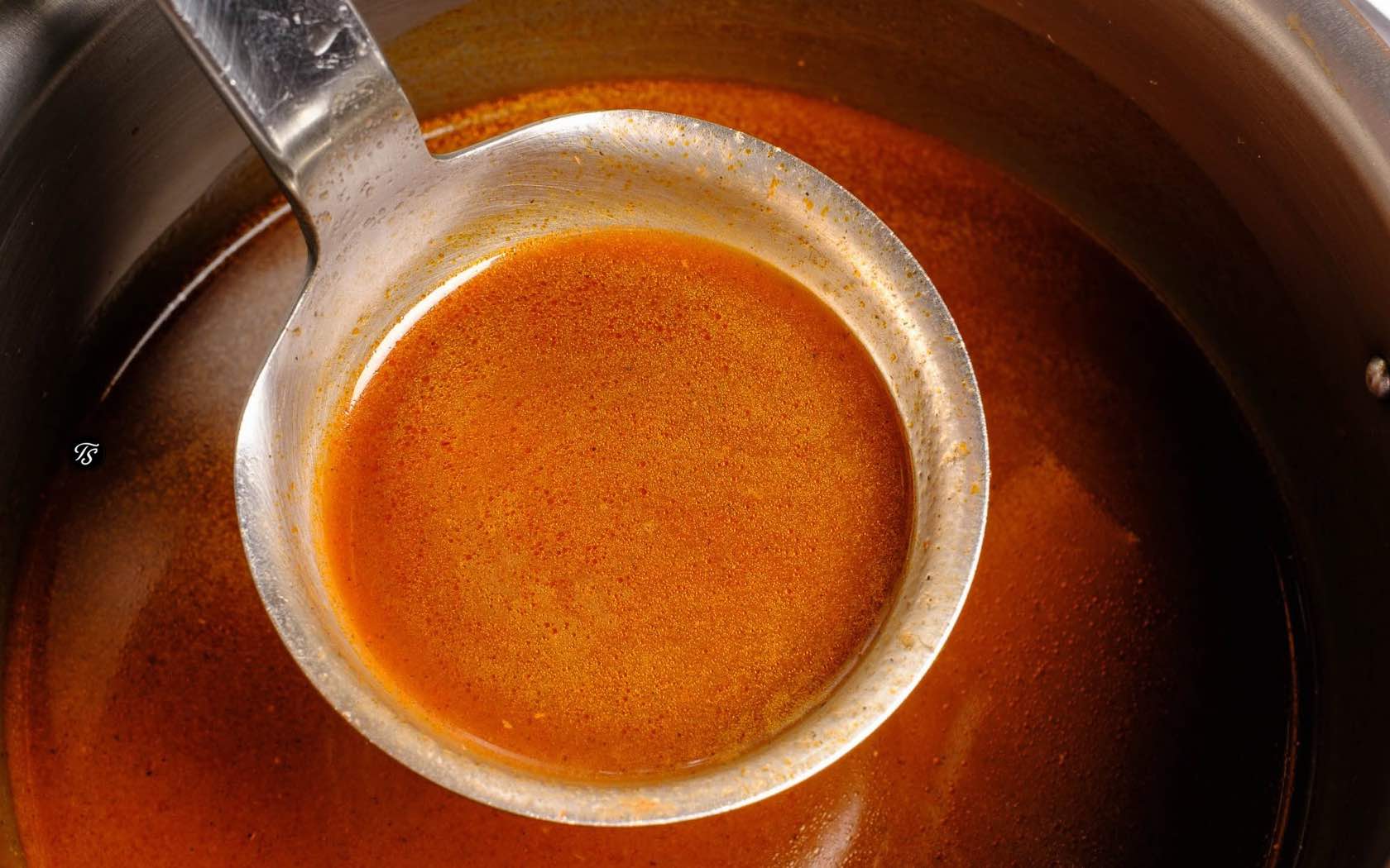 Bratensoße in einem Topf mit gefüllter Schöpfkelle