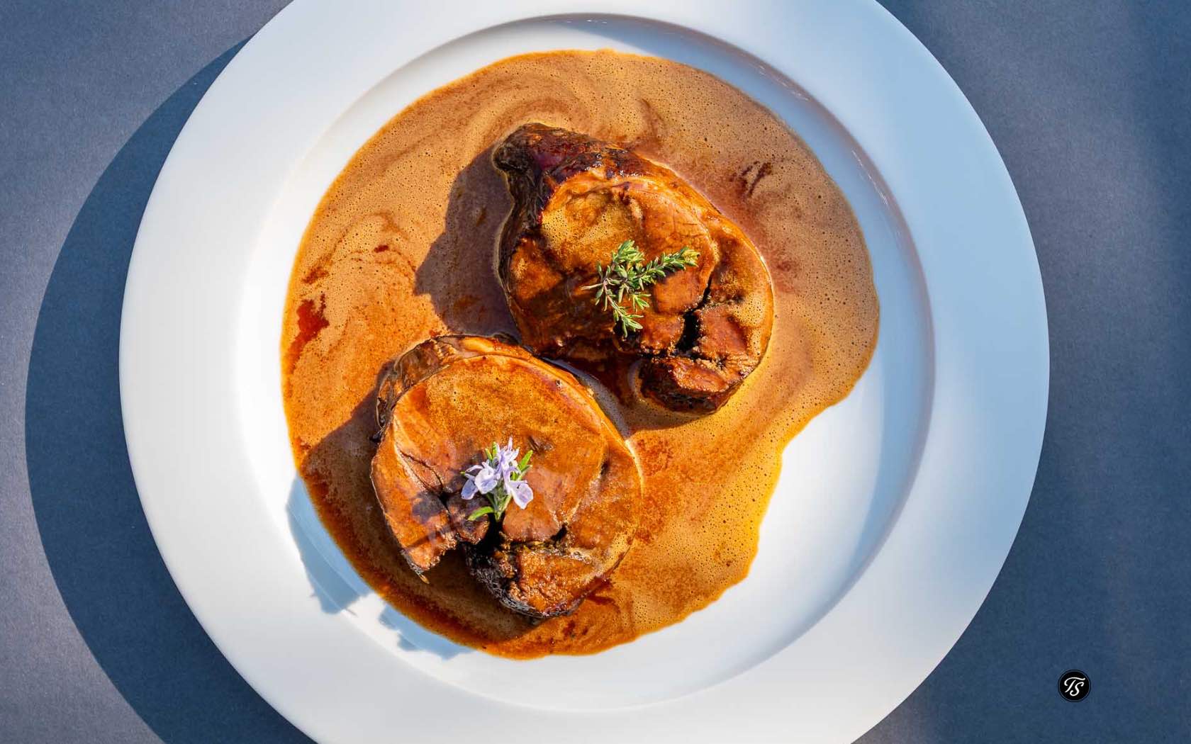 2 Stücke Lammrollbraten mit Soße auf einem weißen Teller