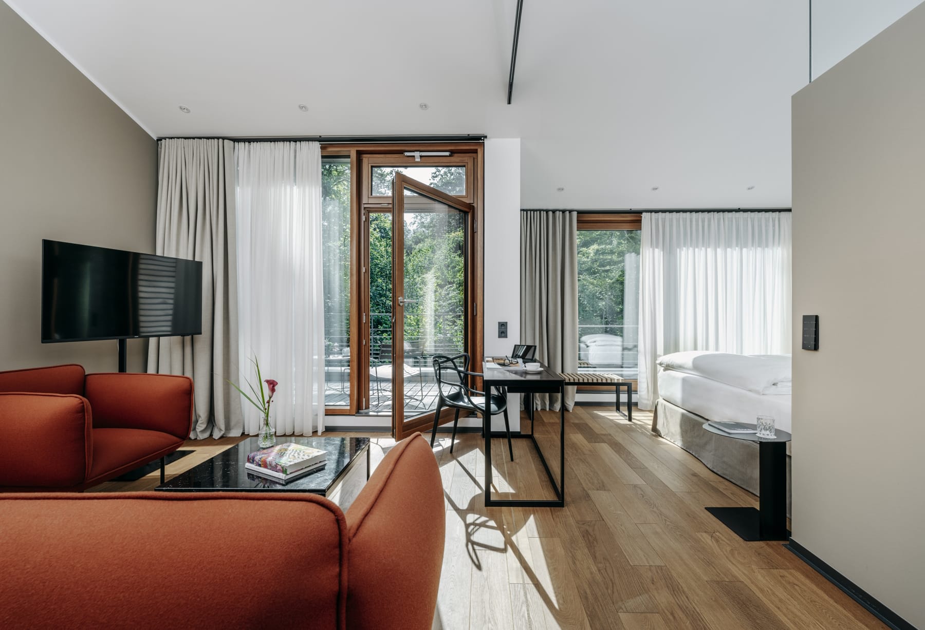 2025_07_Diepschrather Mühle Zimmer mit bodentiefen Fenstern und Lounge mit Blick ins Grüne