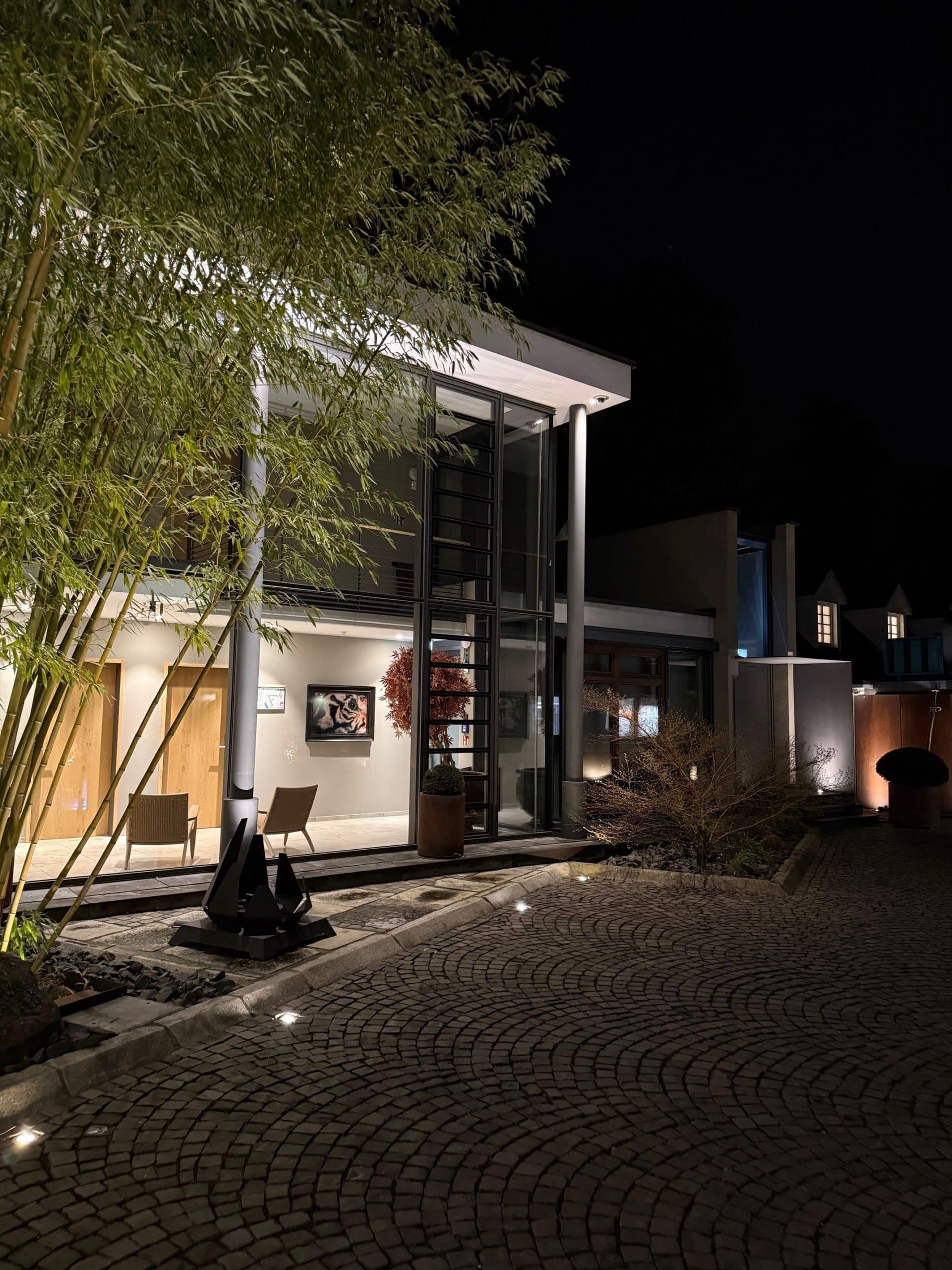 Blick auf den Innenhof und das Hotelgebäude der Diepeschrather Mühle bei Nacht.