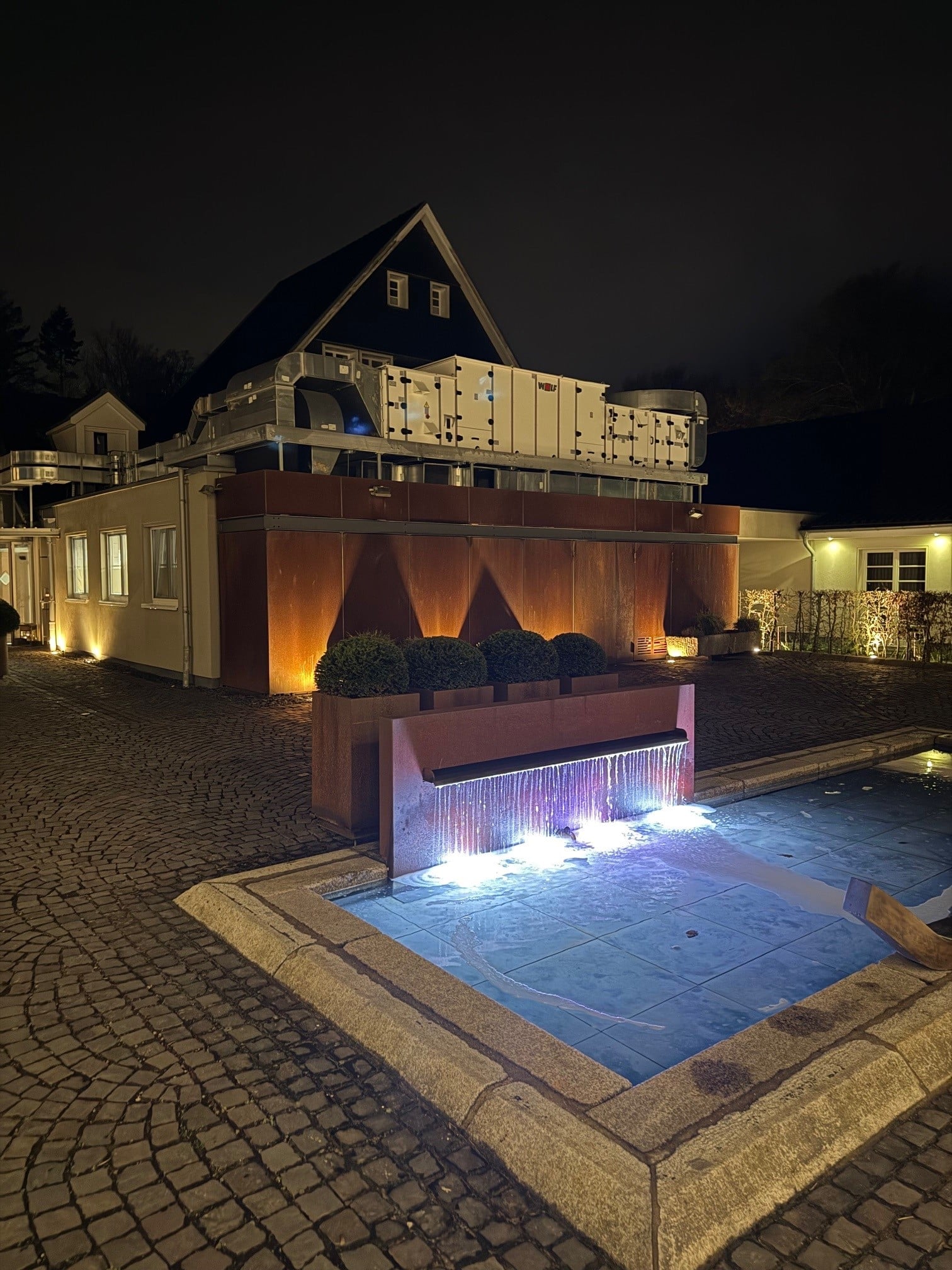 Blick auf die Diepeschrather Mühle mit beleuchtetem Pool bei Nacht