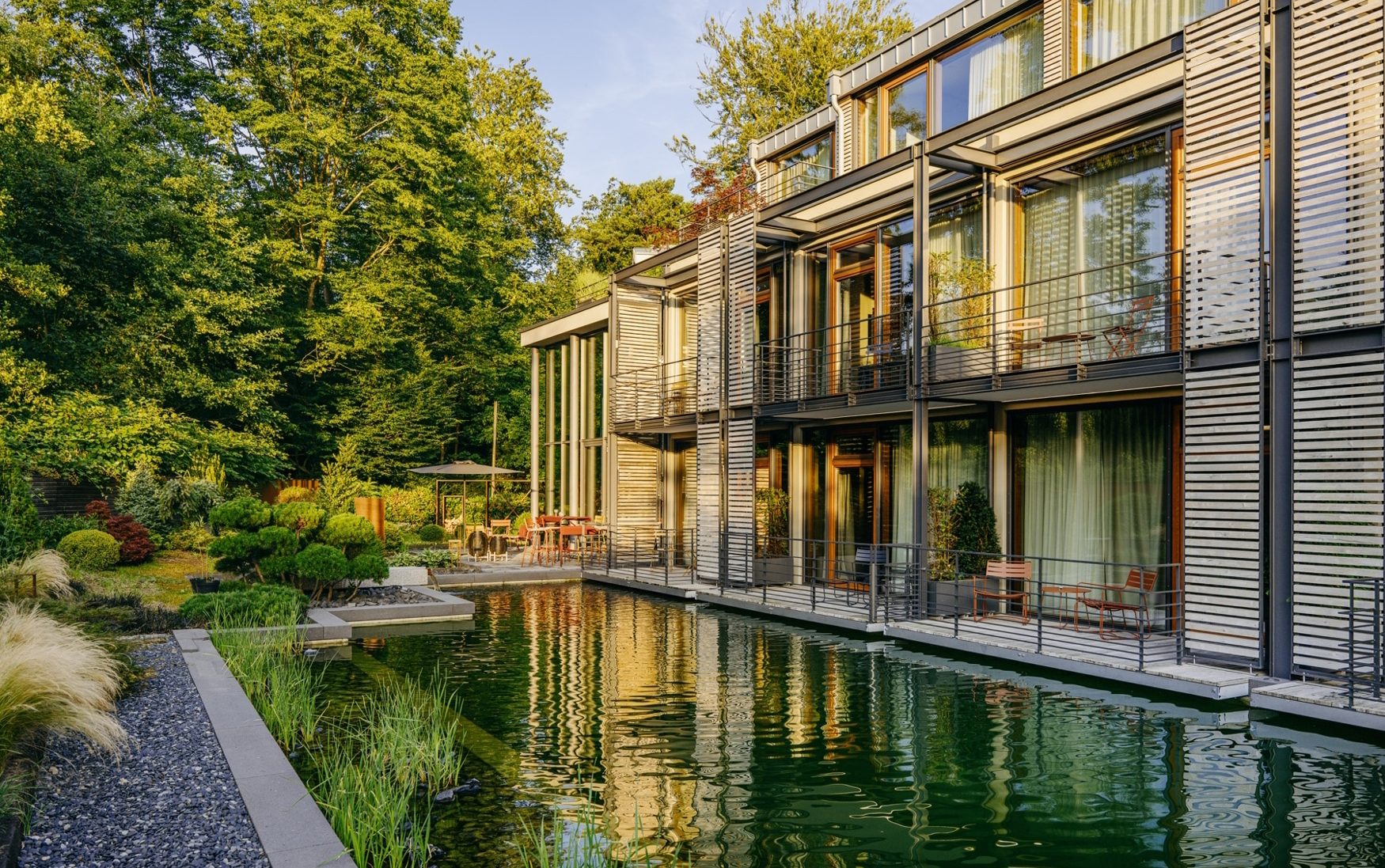 Schwimmteich mit Blick auf die Balkon- und Terrassenzimmer in der Diepeschrather Mühle