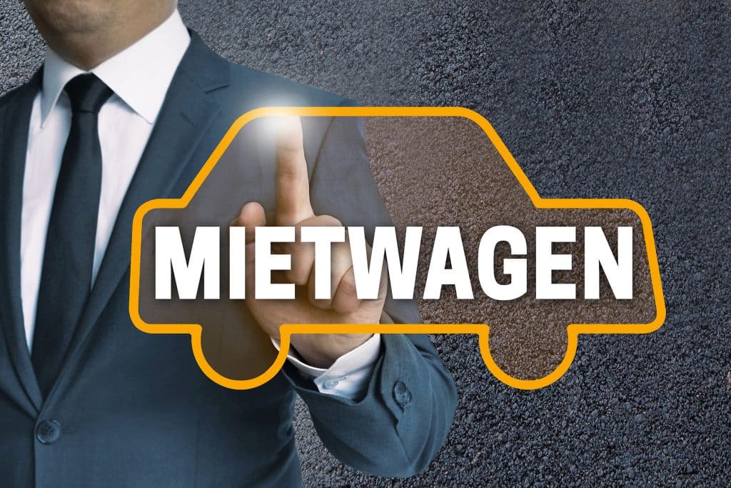 Mann im Anzug berührt Touchscreen in Form eines Mietwagens auf einer Scheibe. Innerhalb der Fahrzeugumrisse befindet sich der Schriftzug MIETWAGEN