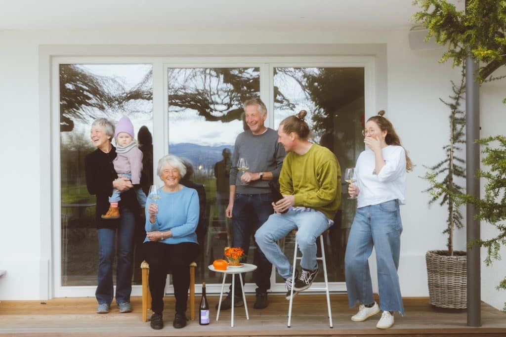 Familie Hornstein – Seehaldenhof Familienfoto auf der Hausterrasse mit Weingläsern. Im Fenster spiegel sich de See