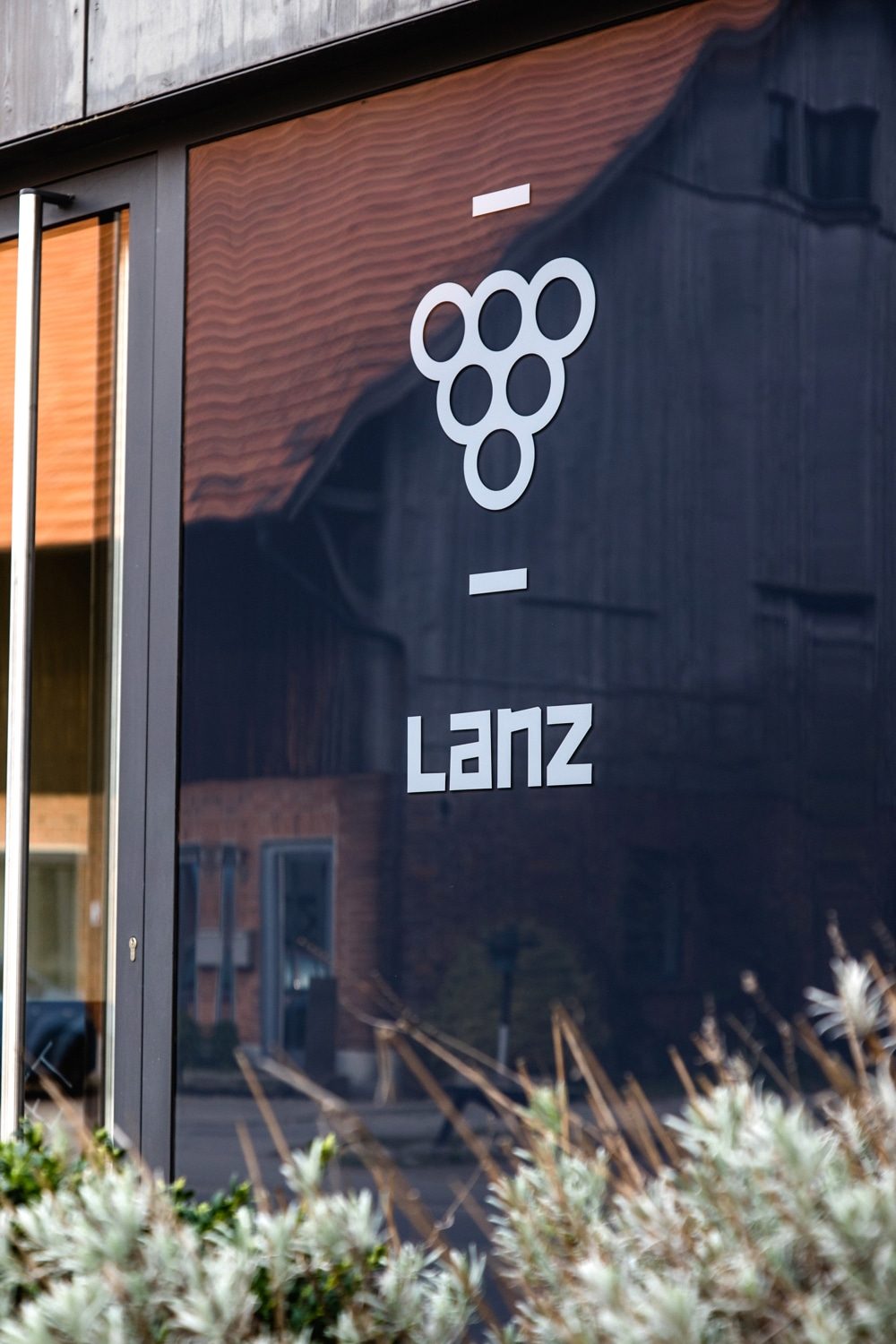 Logo Weingut Lanz Traubenlogo und Name Lanz in weiß auf schwarz-getönter Glastür