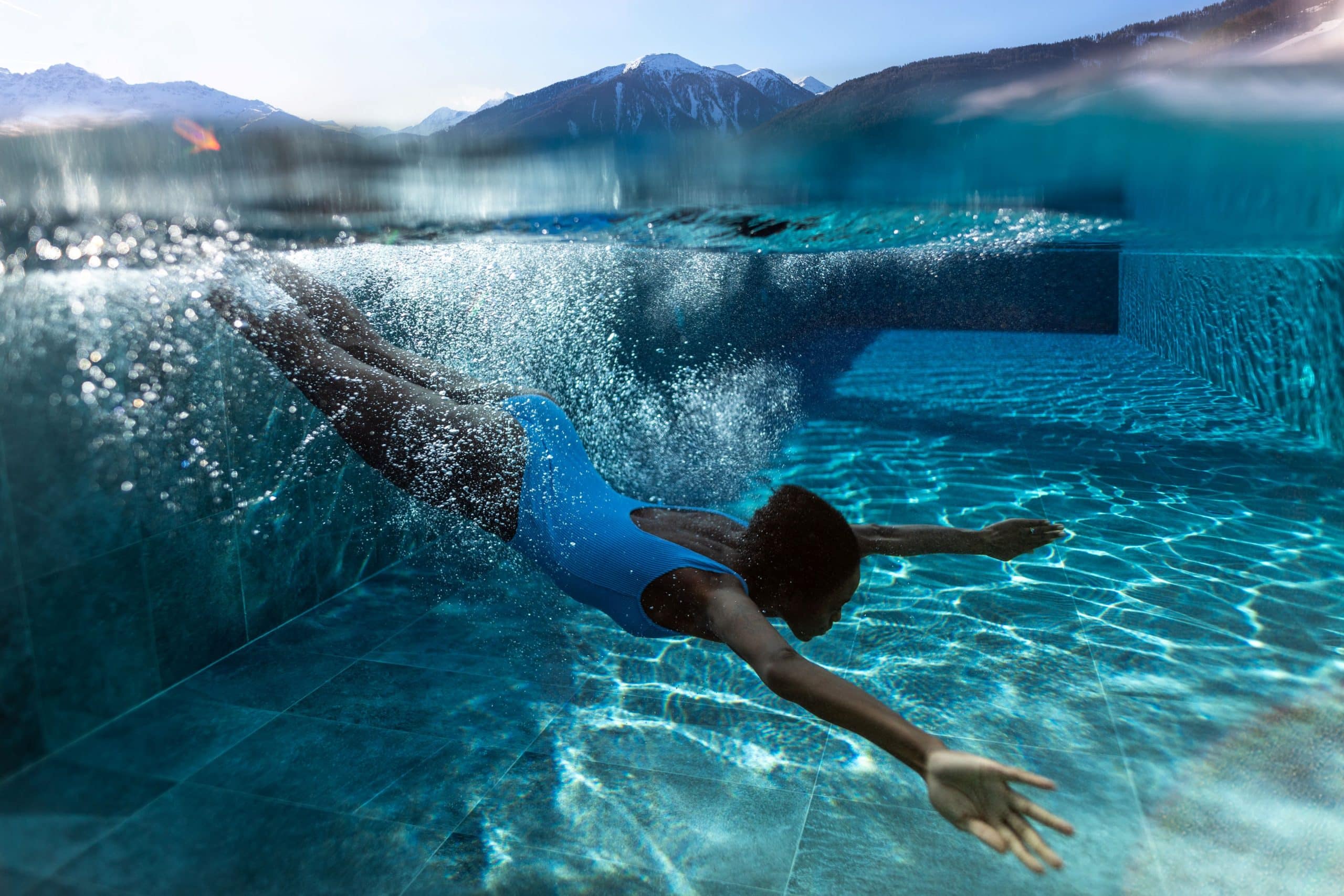 Frau taucht in den Pool, Unterwasserfoto vom Hotel Weisses Kreuz in Mals
