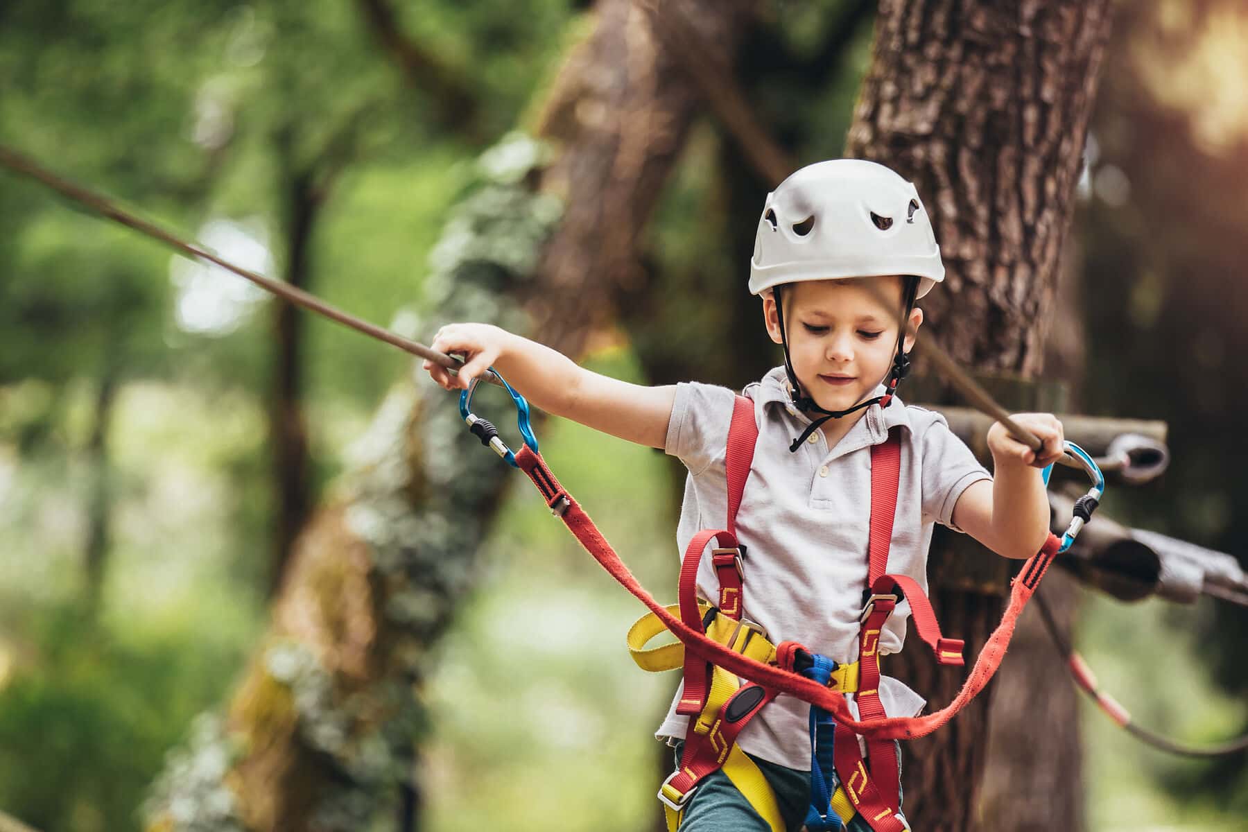 Junge in Kletterausrüstung in einem Kletterwald