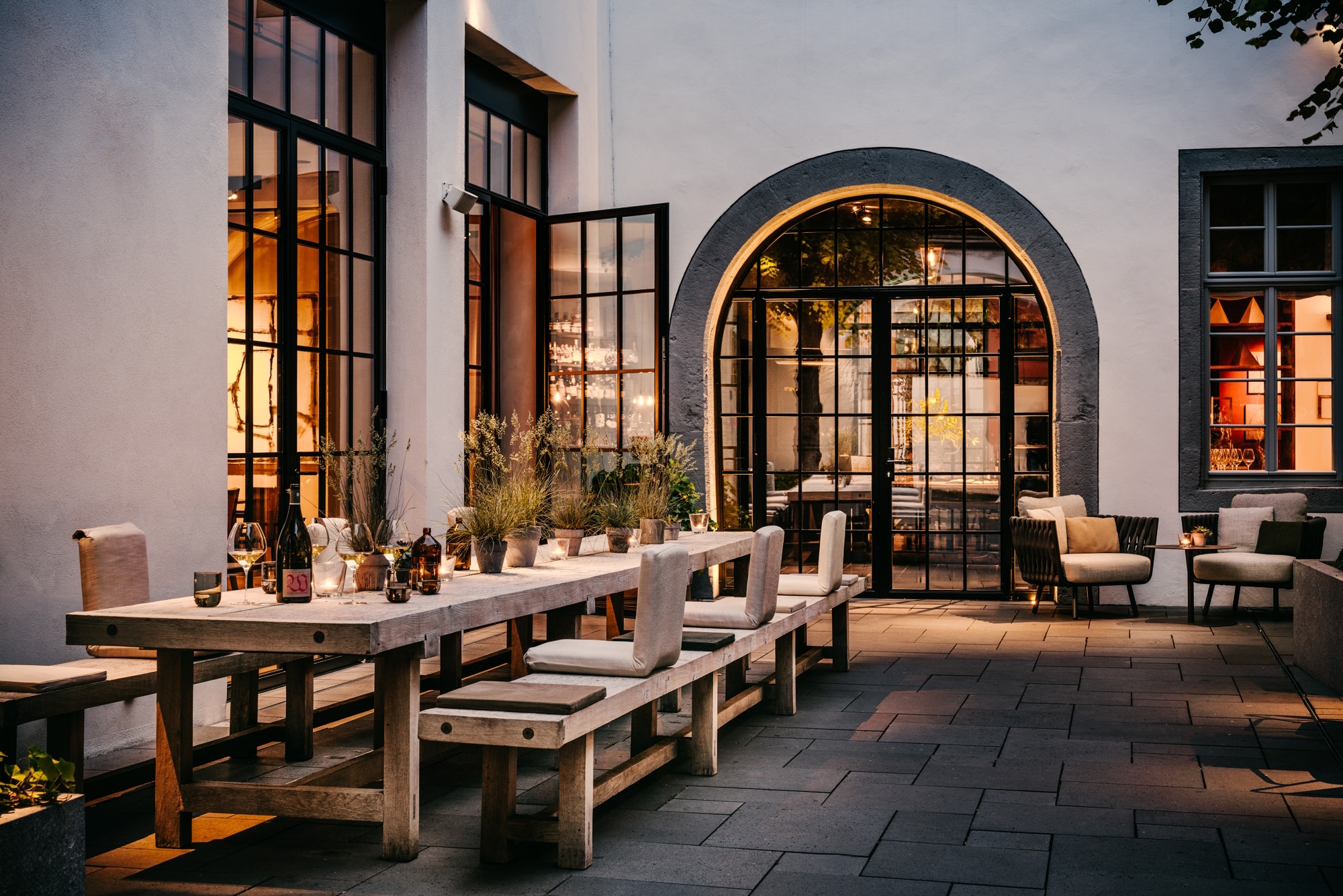 Innenhof im PURS mit langem Holztisch und Bänken mit Rückenlehnen am Abend