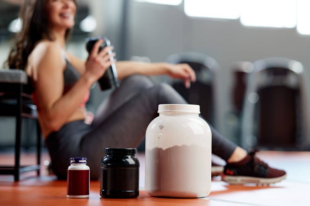 Selective focus on supplements and protein power in gym with a sportswoman. Selective focus on supplements and protein power in gym with a sportswoman.
