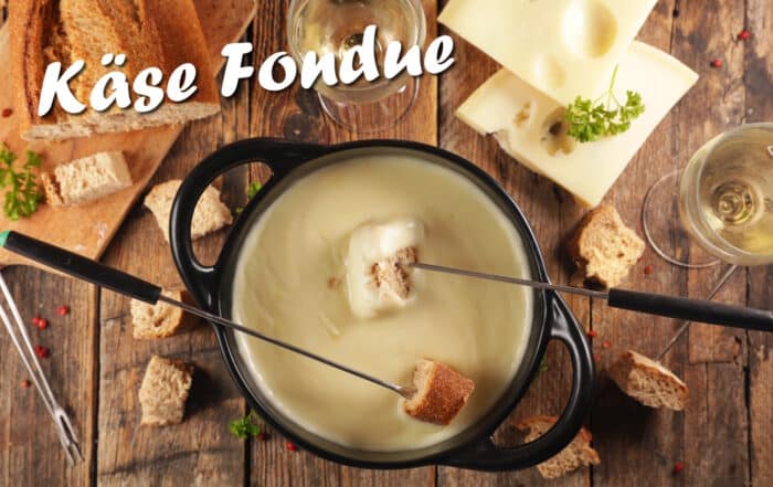 Käsefondue von oben auf einem Holztisch mit Schriftzug Käse Fondue