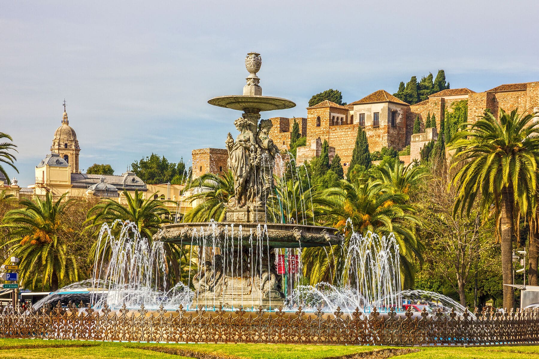 Malaga, Spain – June 14, 2018: Malaga street fountain and Alcazaba fortress. Malaga street fountain and Alcazaba fortress