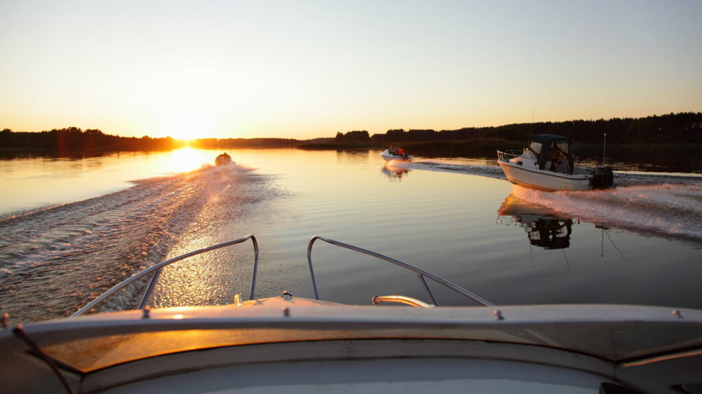 Motorboote fahren auf einem Fluss in den Sonnenuntergang