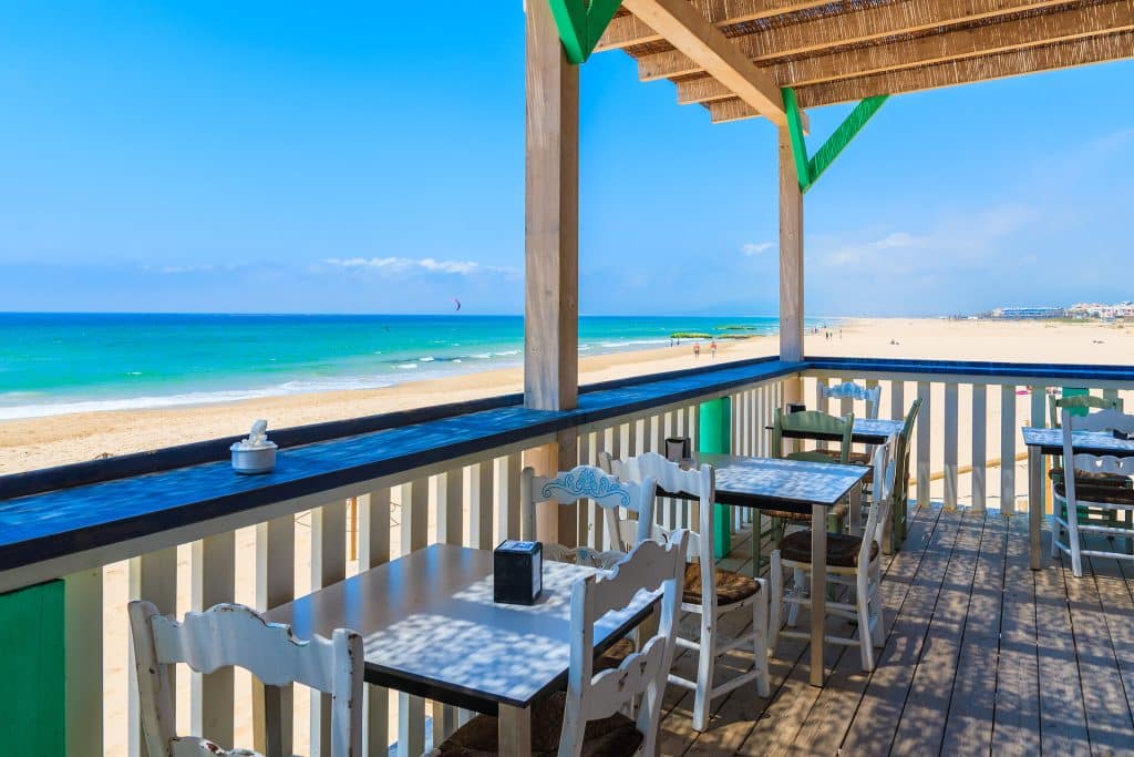 Tarifa Beach Restaurant tables on wooden terrace on sandy beach on Costa de la Luz.