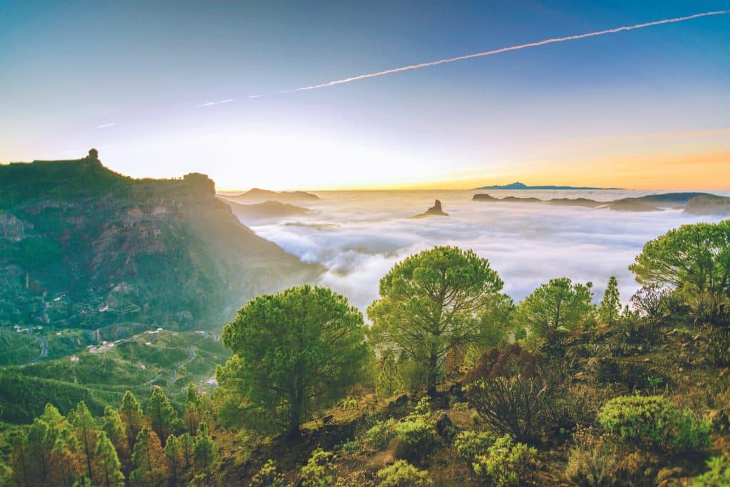 Blick auf Teneriffa und den Teida bei Sonnenuntergang von den Bergen Gran Canarais aus mit rosa gefärbten Kondensstreifen am Himmel
