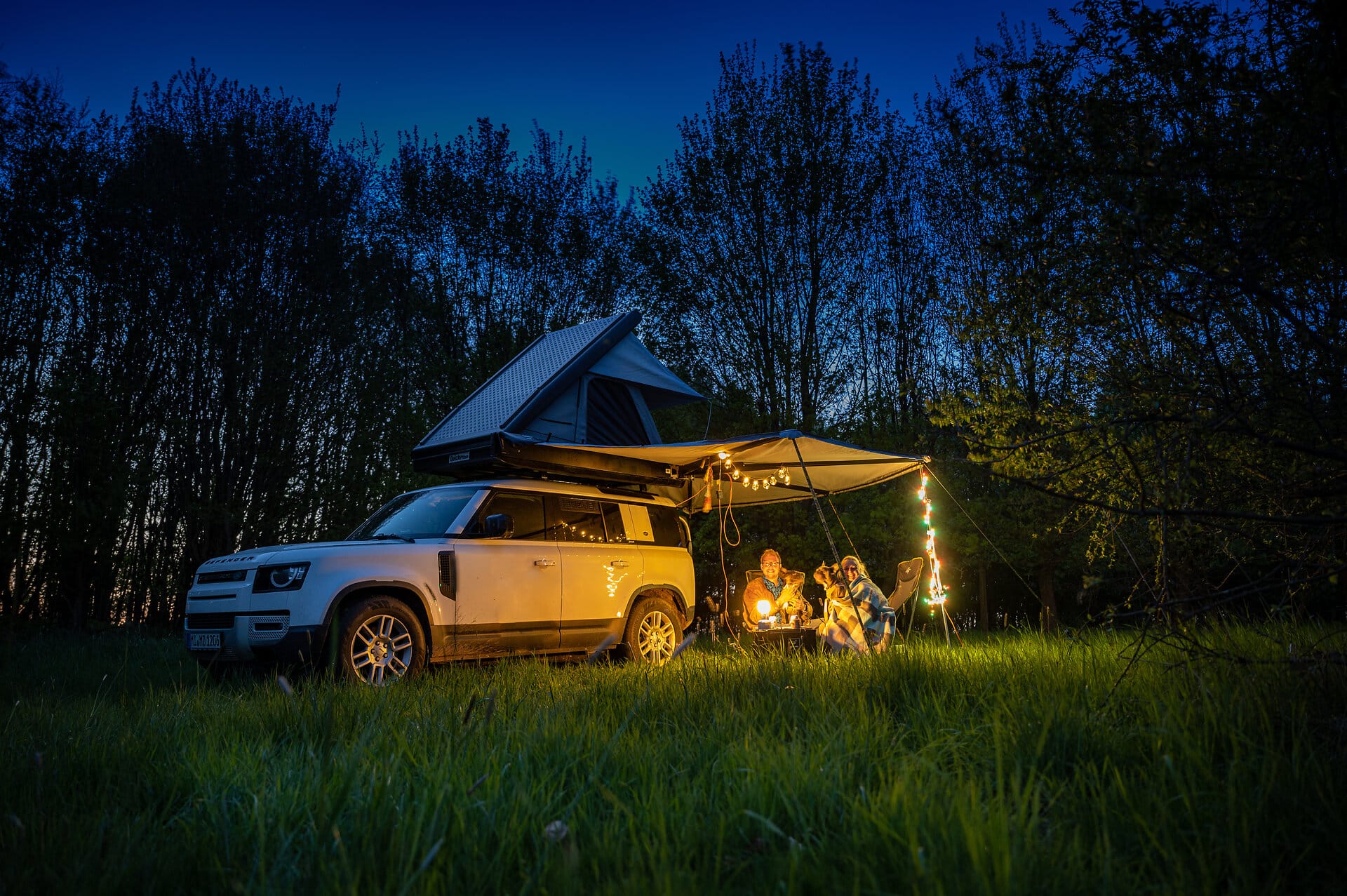 Camping with roof tent romantic evening Abends unter dem Zeltdach im Grünen mit Lichterkette und Dachzelt auf 4x4 Auto