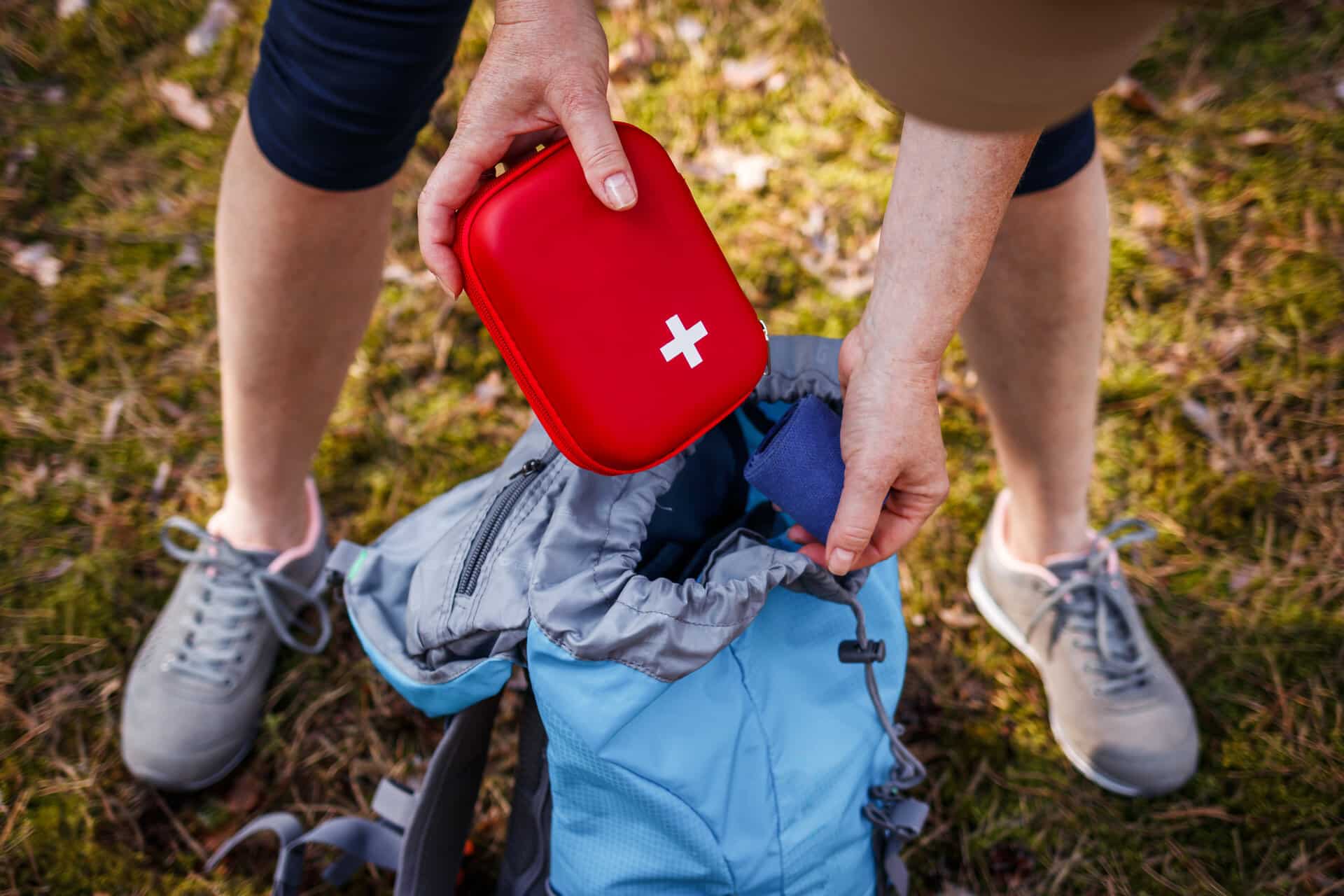 Frau steckt rotes Täschchen mit Reiseapotheke in einen Rucksack