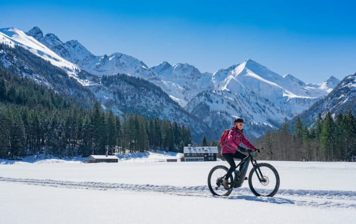 Frau fährt mit dem Fahrrad durch Allgäuer Schneelandschaft