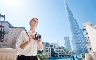 Junge, blonde Frau mit Fotoakamera in Dubai bei Sonnenschein