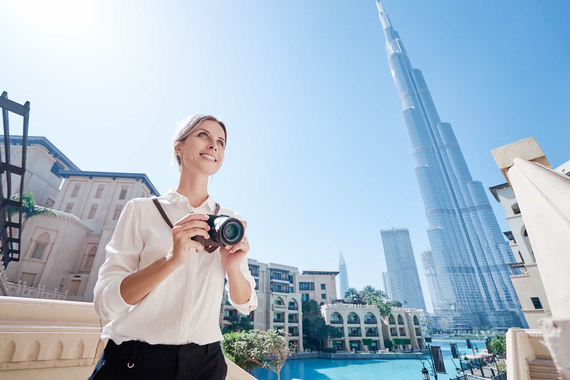 Junge, blonde Frau mit Fotoakamera in Dubai bei Sonnenschein