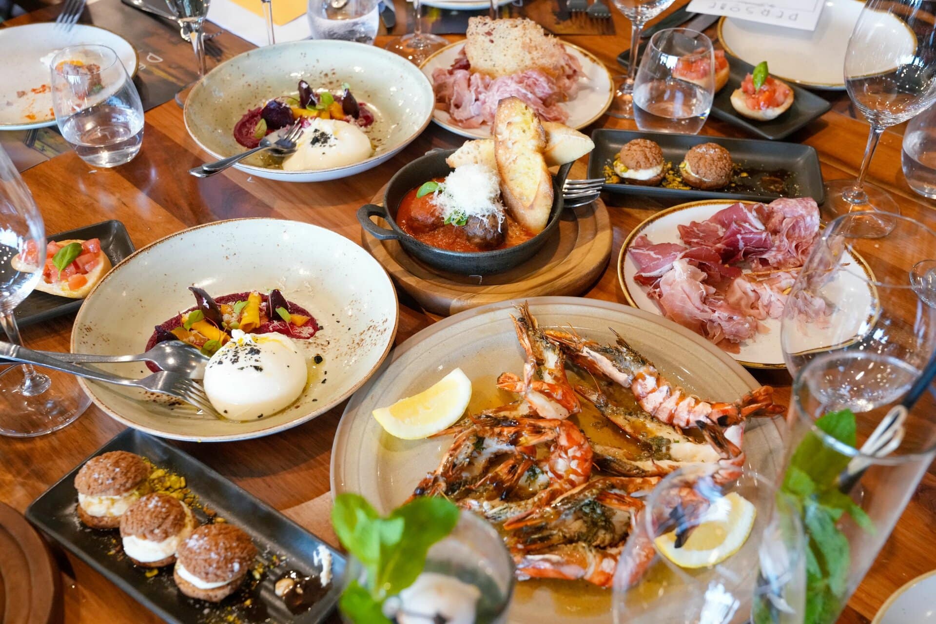 Spanische Tapas und gegrillte Garnelen auf verschidenen Tellern und Schälchen auf einem Tisch.