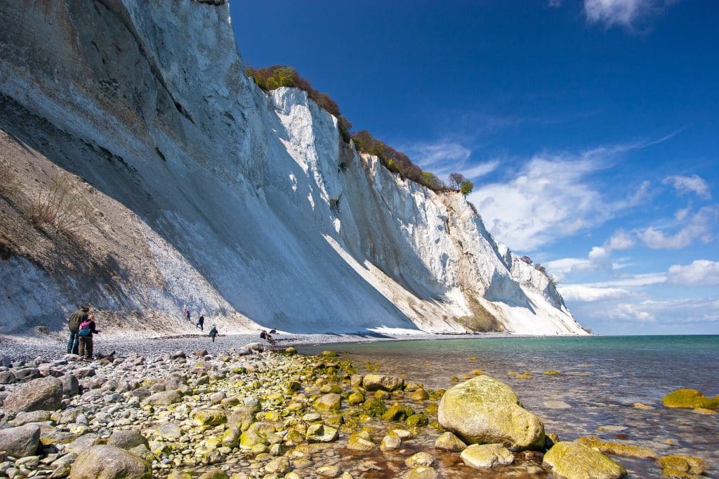 Kreidefelsen von Møns Klint in Dänemark an einem sonnigen Tag vom Strand aus fotografiert mit Spaziergängern