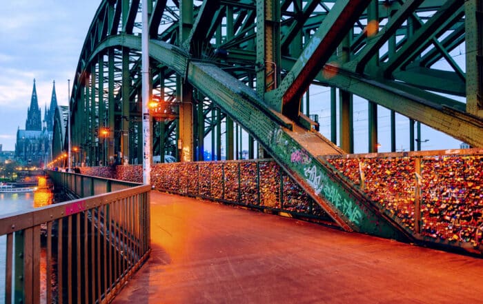 Auf der Hohenzollernbrücke in Köln beleuchtet am Abend mit Kölner Dom im Hintergrund