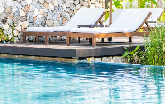 Liegestühle am Outdoor Pool vor Natursteinmauer