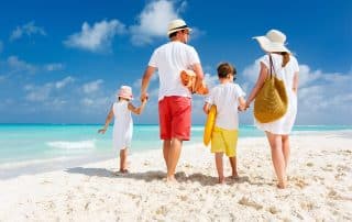 Back view of a happy family at tropical beach on summer vacation