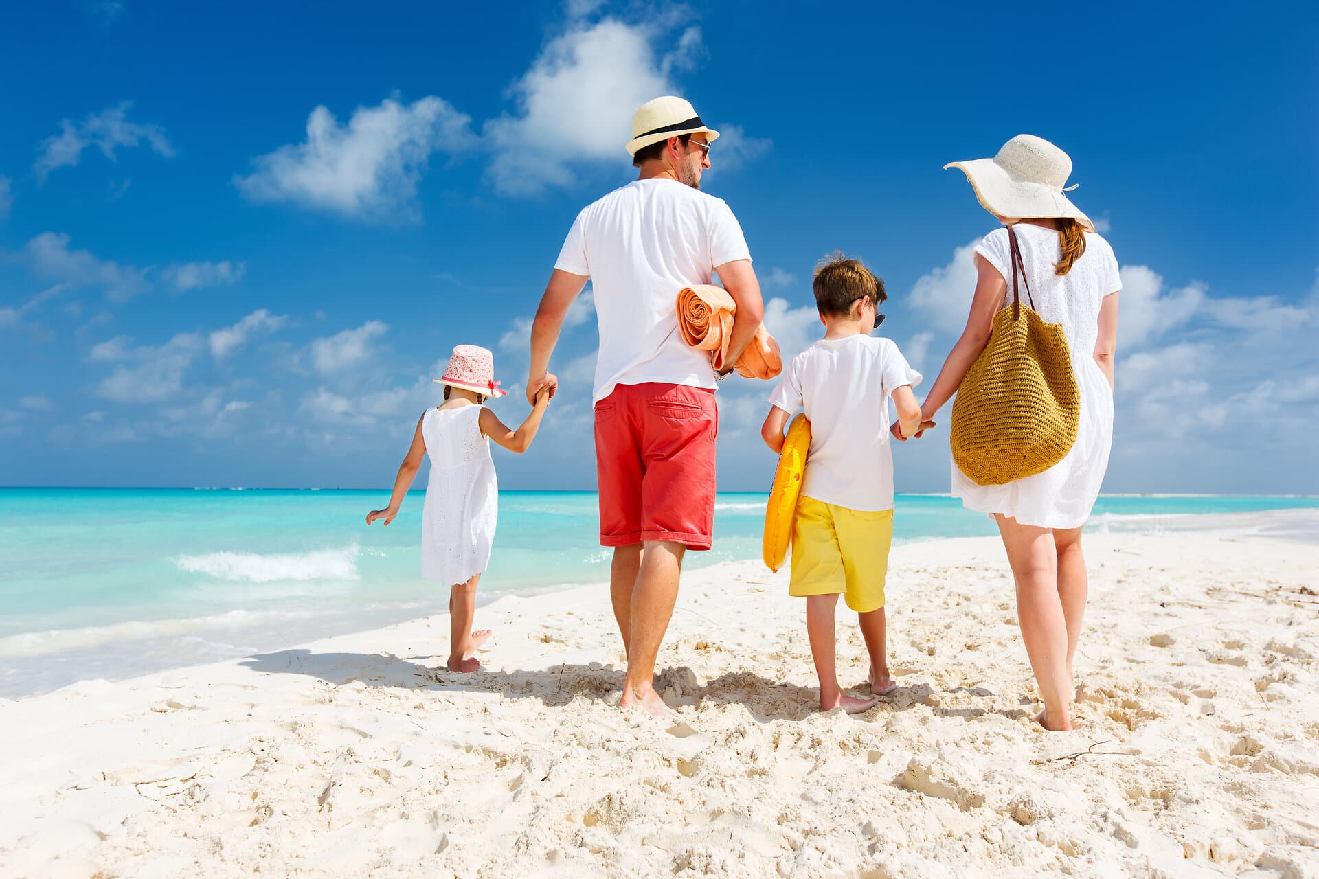 Back view of a happy family at tropical beach on summer vacation