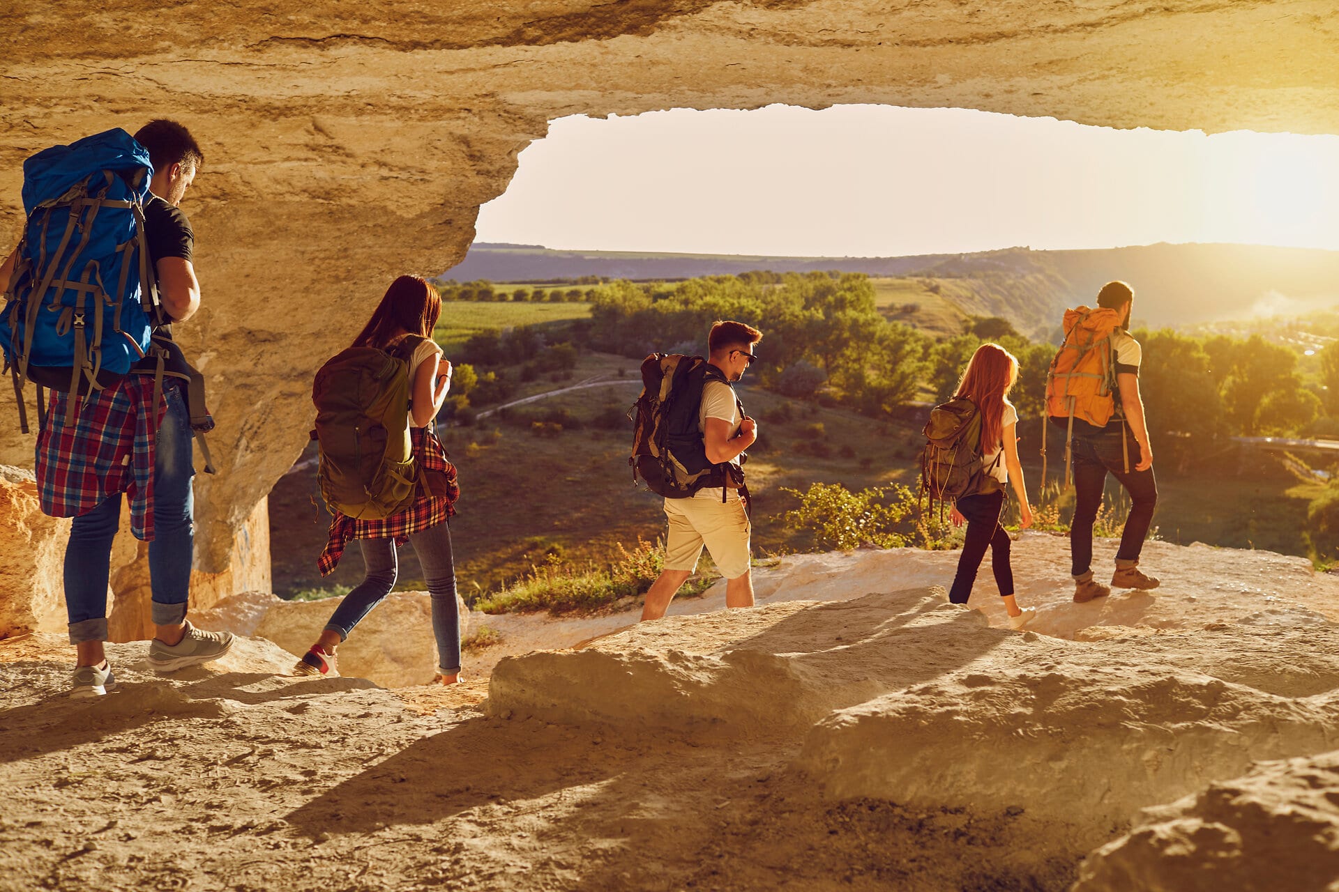 Group of young tourists hikers hiking in natural rocks with backpacks