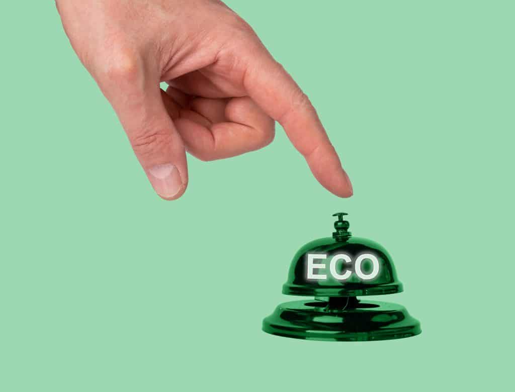 Hand pressing reception bell with word eco. Choice in favor of ecology and environmentally friendly products in hotel, store, cafe, restaurant