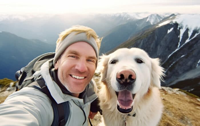 Mann mit Hund bei einer Wanderung in den Bergen macht Selfies