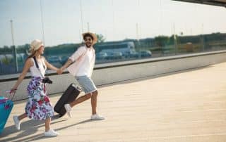 Junges Paar mit Koffern am Flughafen läuft schnell zum Flieger. Spontan verreisen.