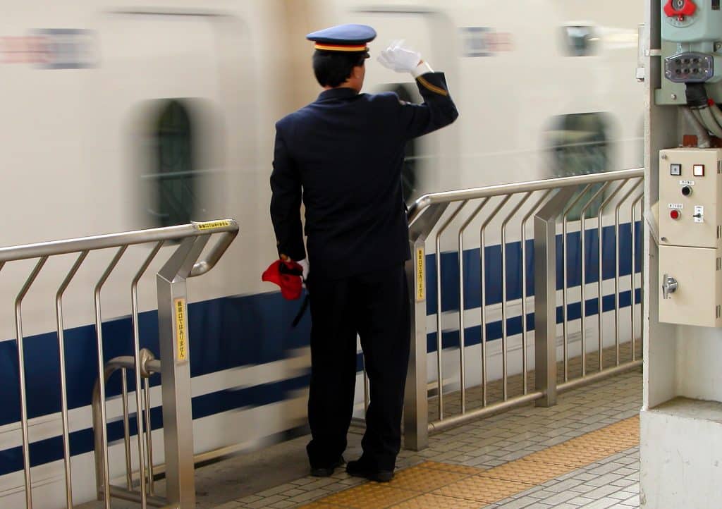 Conductor waves to departing train, an aspect from Kyoto Railway Station, Japan